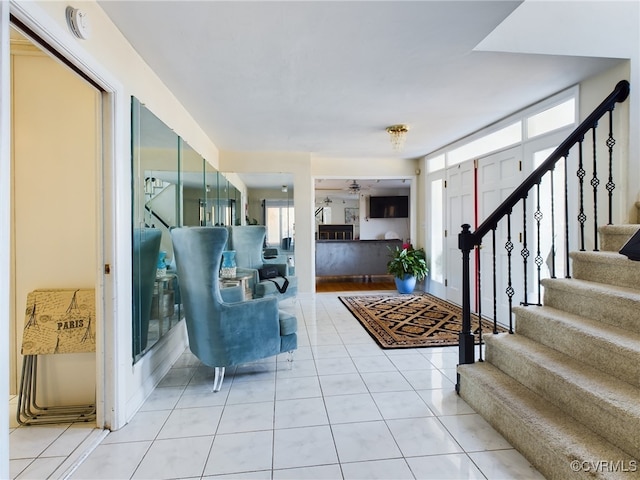 entrance foyer featuring light tile patterned floors, plenty of natural light, and stairs