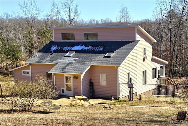 view of front of house featuring a shingled roof, a patio area, and a front lawn