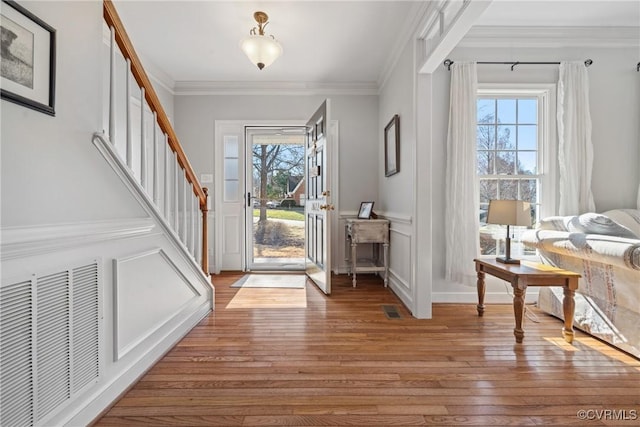 entrance foyer with light wood finished floors, plenty of natural light, visible vents, and ornamental molding