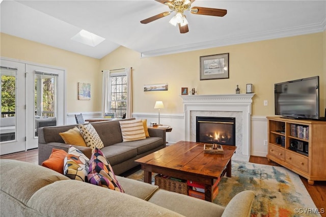 living room with a premium fireplace, a wainscoted wall, ceiling fan, and wood finished floors