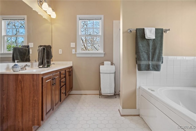 bathroom with plenty of natural light, a sink, a garden tub, and double vanity