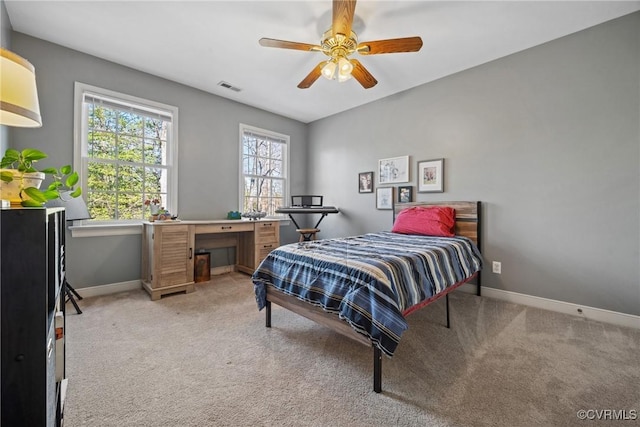 bedroom with visible vents, light colored carpet, baseboards, and ceiling fan