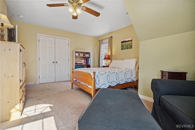 bedroom with a closet, baseboards, light colored carpet, and ceiling fan