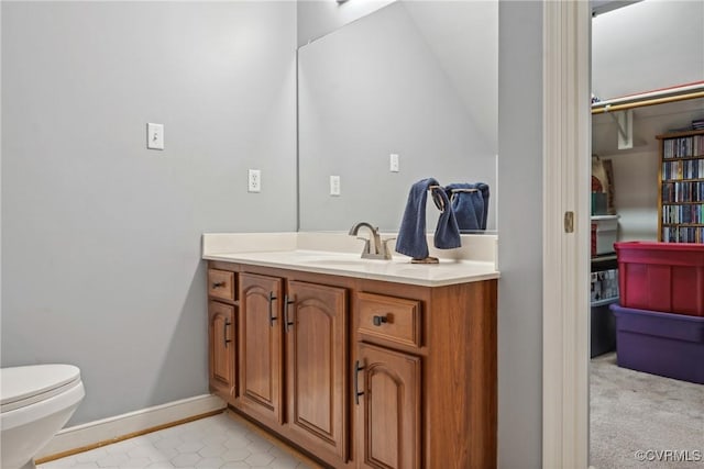 bathroom with baseboards, toilet, and vanity