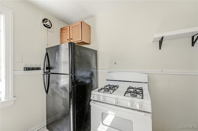 kitchen featuring plenty of natural light, freestanding refrigerator, visible vents, and white gas stove