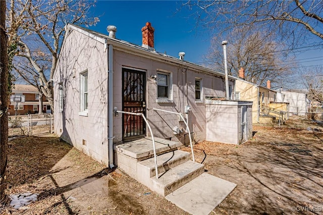 back of house with crawl space, a chimney, and fence