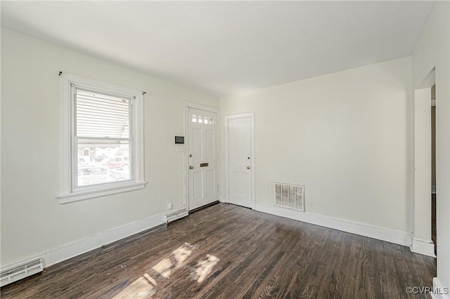 unfurnished room featuring dark wood-style flooring, visible vents, and baseboards