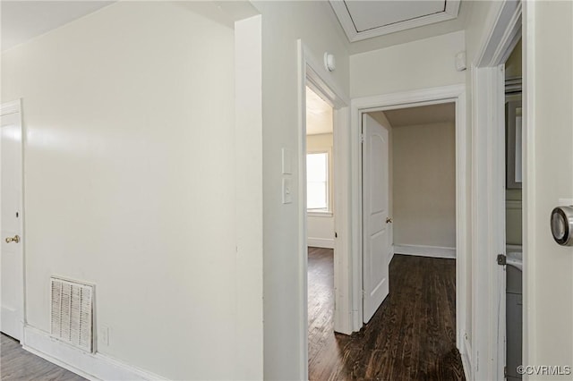 hallway with baseboards, visible vents, and dark wood-type flooring