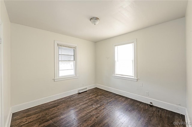 empty room with dark wood-style floors, a healthy amount of sunlight, visible vents, and baseboards