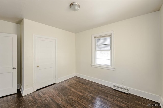 unfurnished bedroom with dark wood-style floors, visible vents, and baseboards