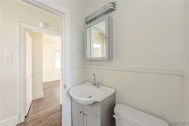 bathroom with toilet, baseboards, wood finished floors, and vanity