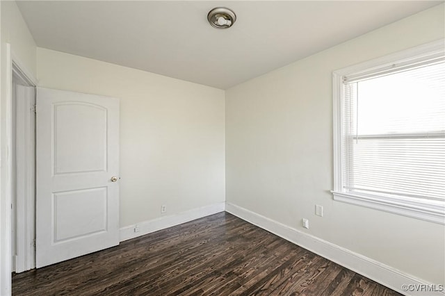 spare room with dark wood-style flooring and baseboards