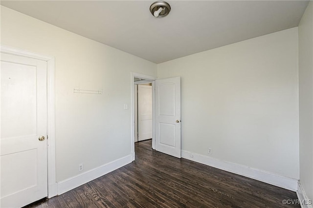 empty room featuring dark wood-style floors and baseboards