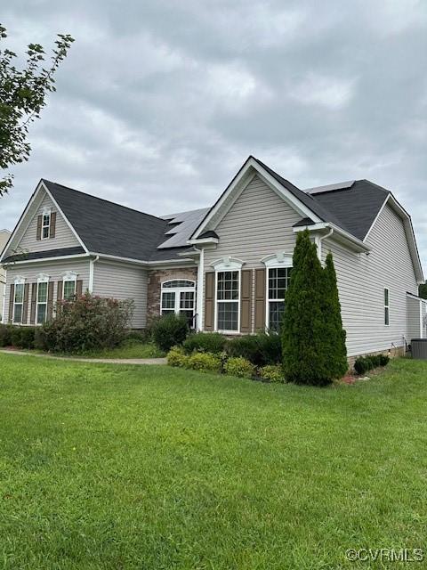 view of front of property with roof mounted solar panels and a front lawn