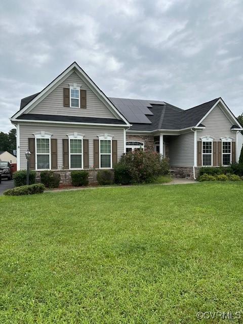 view of front of house with a front yard and roof mounted solar panels