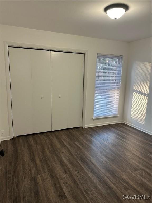 unfurnished bedroom featuring a closet and dark wood finished floors