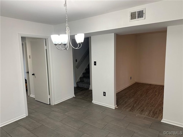 unfurnished dining area with visible vents, a notable chandelier, baseboards, and stairs