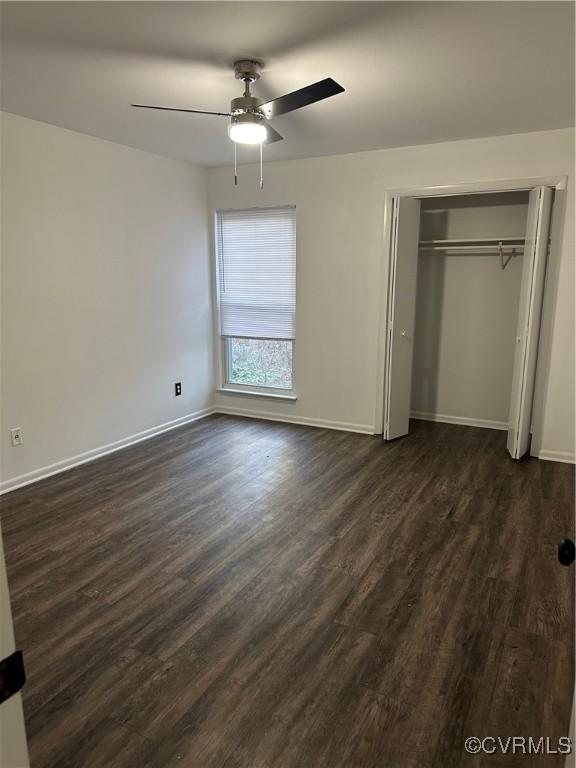 unfurnished bedroom featuring ceiling fan, a closet, baseboards, and dark wood-type flooring