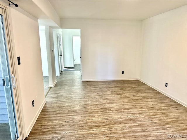 spare room with baseboards and wood finished floors