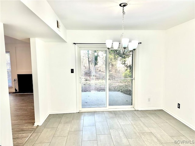 unfurnished dining area with a chandelier, visible vents, baseboards, and wood finished floors