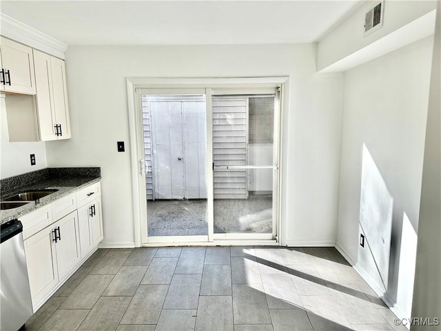 kitchen with visible vents, baseboards, white cabinetry, stainless steel dishwasher, and dark stone counters