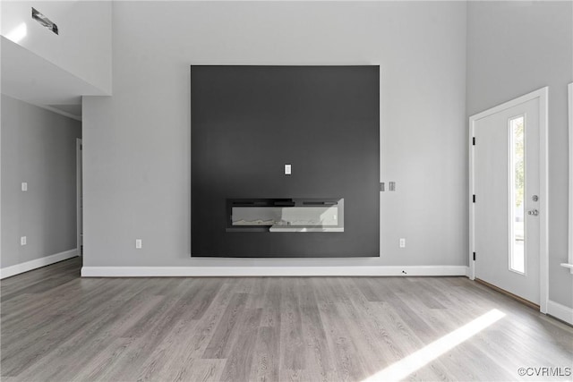 foyer entrance featuring plenty of natural light, a high ceiling, baseboards, and light wood-style flooring