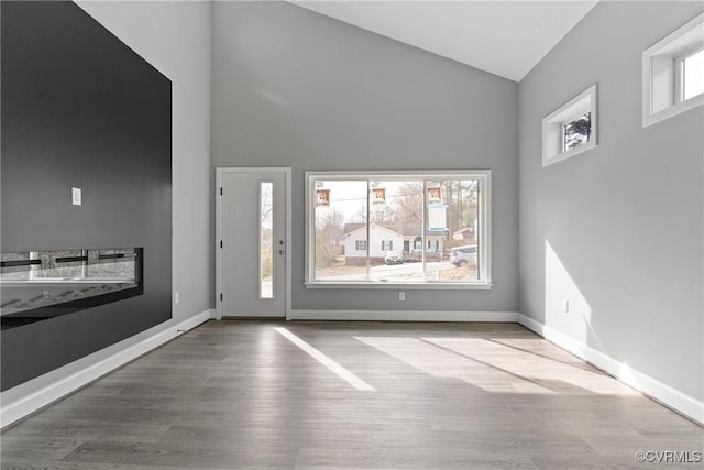 entryway featuring light wood-style floors, high vaulted ceiling, and baseboards