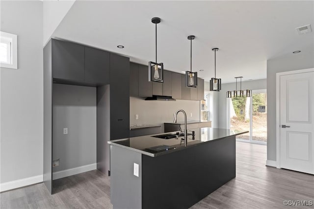 kitchen featuring dark countertops, visible vents, hanging light fixtures, a sink, and modern cabinets