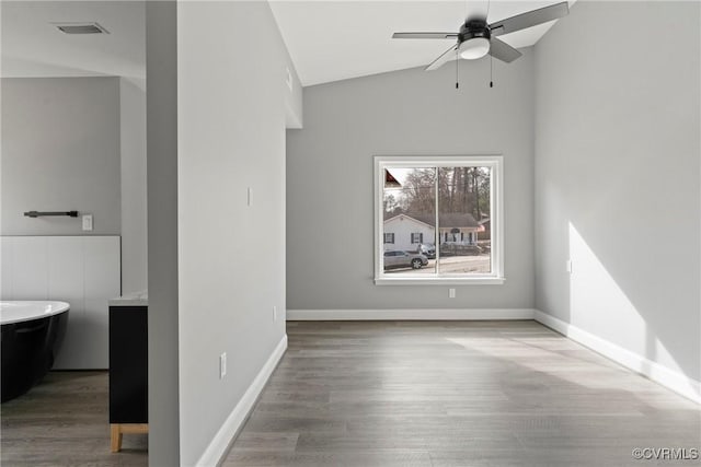 interior space with vaulted ceiling, wood finished floors, visible vents, and a ceiling fan