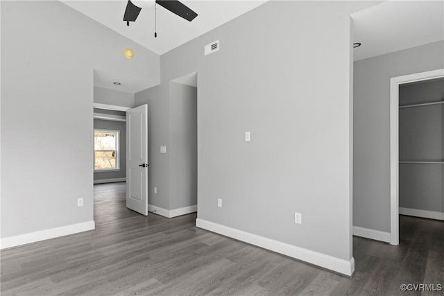 unfurnished bedroom with visible vents, baseboards, a walk in closet, and wood finished floors