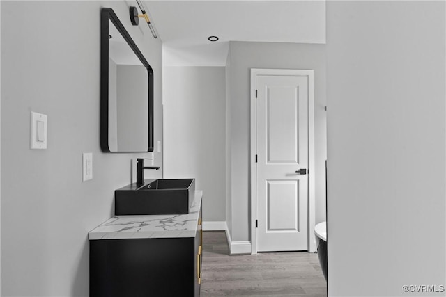 full bathroom featuring vanity, baseboards, and wood finished floors