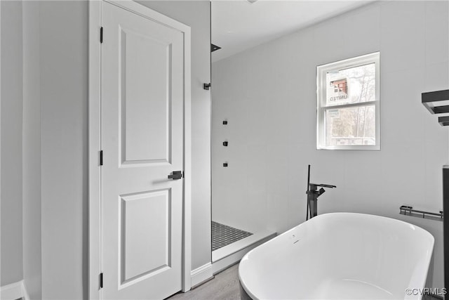 bathroom with a walk in shower, a soaking tub, and wood finished floors