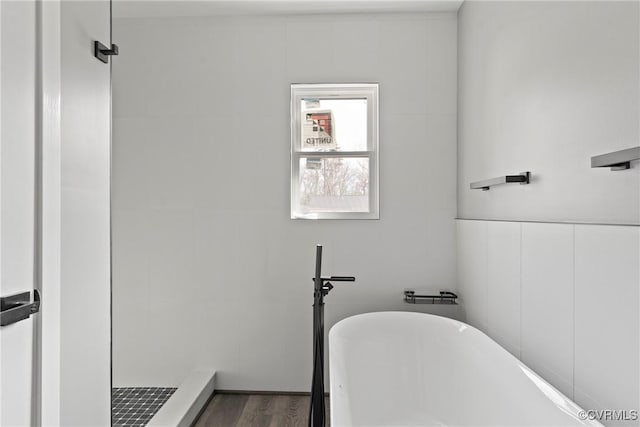 full bathroom with a stall shower, a soaking tub, and wood finished floors