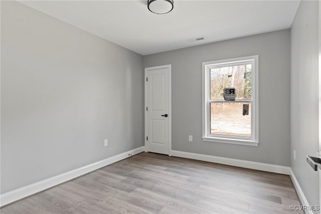 unfurnished room with light wood-style floors, visible vents, and baseboards