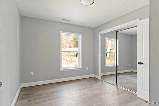 unfurnished bedroom with a closet, baseboards, visible vents, and light wood finished floors