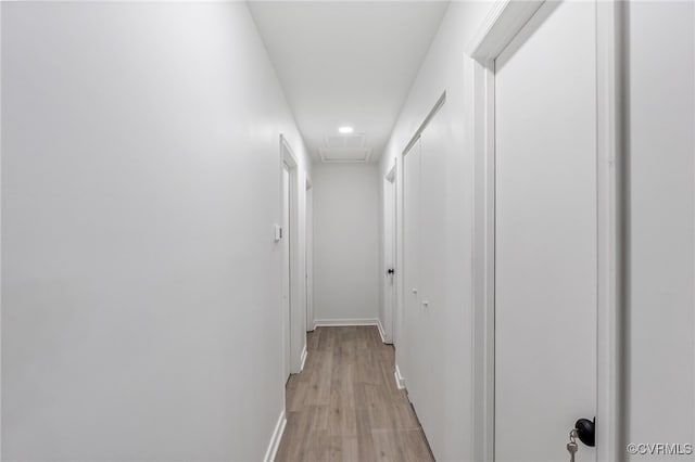 corridor featuring light wood-type flooring, attic access, and baseboards