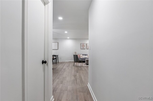 hall featuring light wood finished floors, baseboards, and recessed lighting