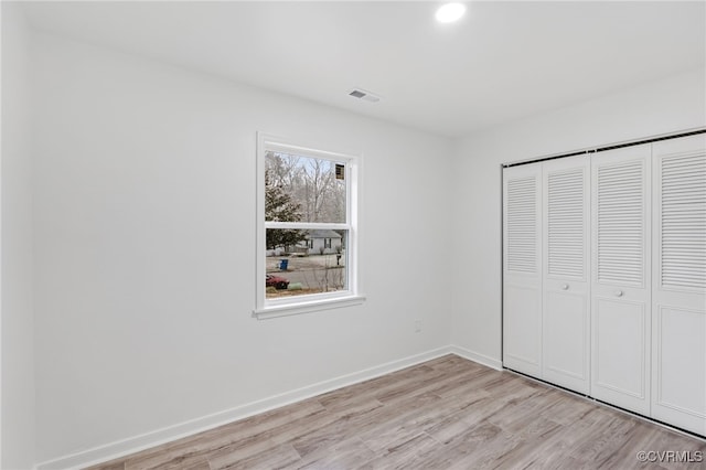 unfurnished bedroom with light wood-type flooring, a closet, visible vents, and baseboards