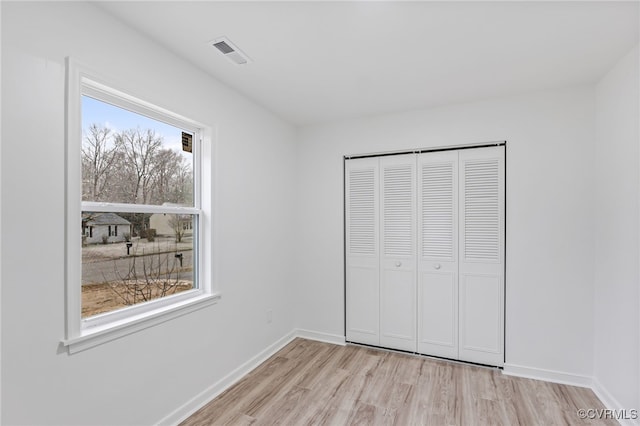 unfurnished bedroom featuring light wood finished floors, a closet, visible vents, and baseboards