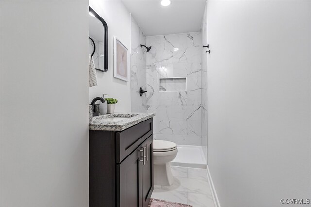 full bath featuring toilet, marble finish floor, a marble finish shower, and vanity