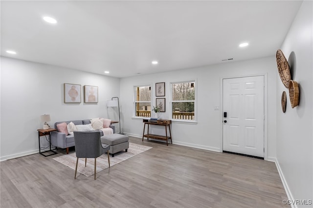 living area featuring baseboards, light wood finished floors, and recessed lighting