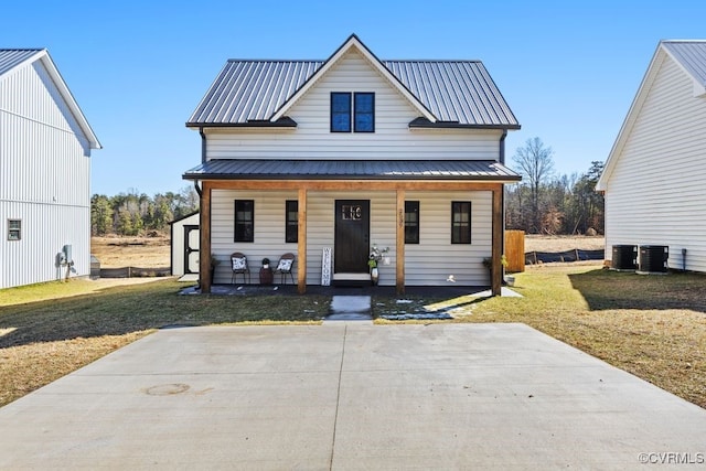 view of front of house with central AC, metal roof, a porch, and a front lawn