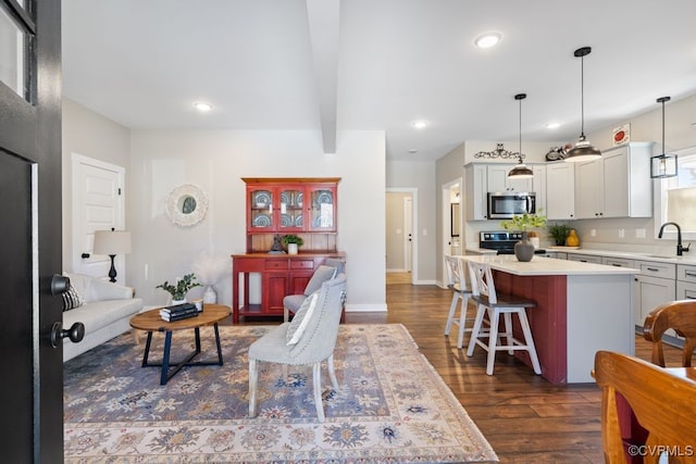 living room featuring baseboards, beamed ceiling, dark wood finished floors, and recessed lighting