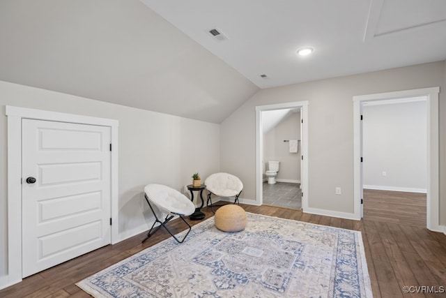 living area featuring baseboards, visible vents, vaulted ceiling, and wood finished floors