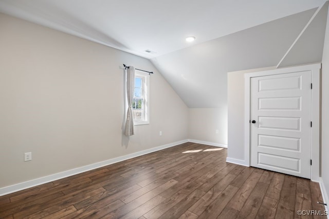 additional living space with vaulted ceiling, dark wood-style flooring, and baseboards