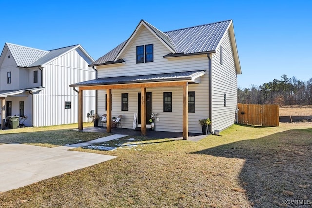 modern farmhouse featuring metal roof, a porch, fence, and a front lawn