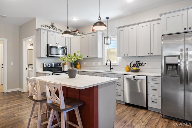 kitchen with stainless steel appliances, pendant lighting, light countertops, and a sink