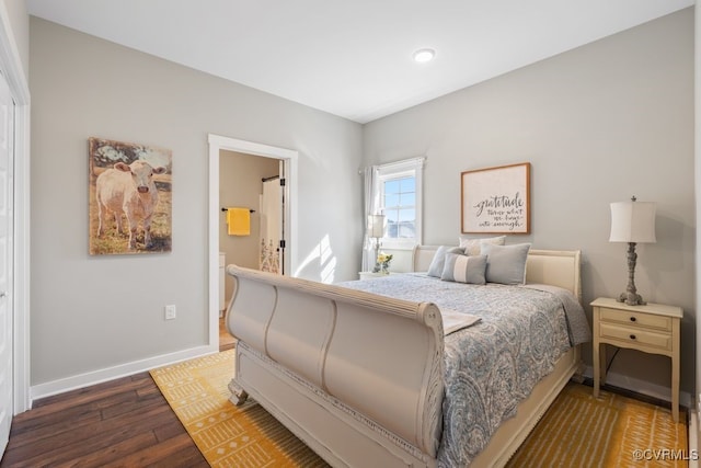 bedroom with connected bathroom, baseboards, and wood finished floors