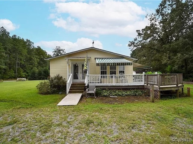 rear view of property featuring a lawn, french doors, and a wooden deck