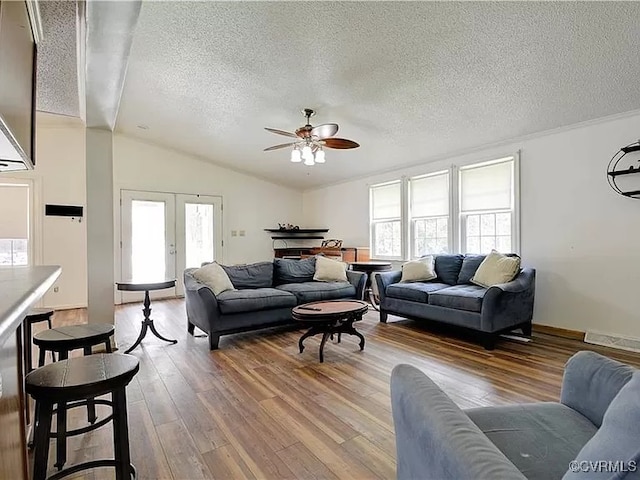 living room with plenty of natural light, lofted ceiling, wood finished floors, and a ceiling fan